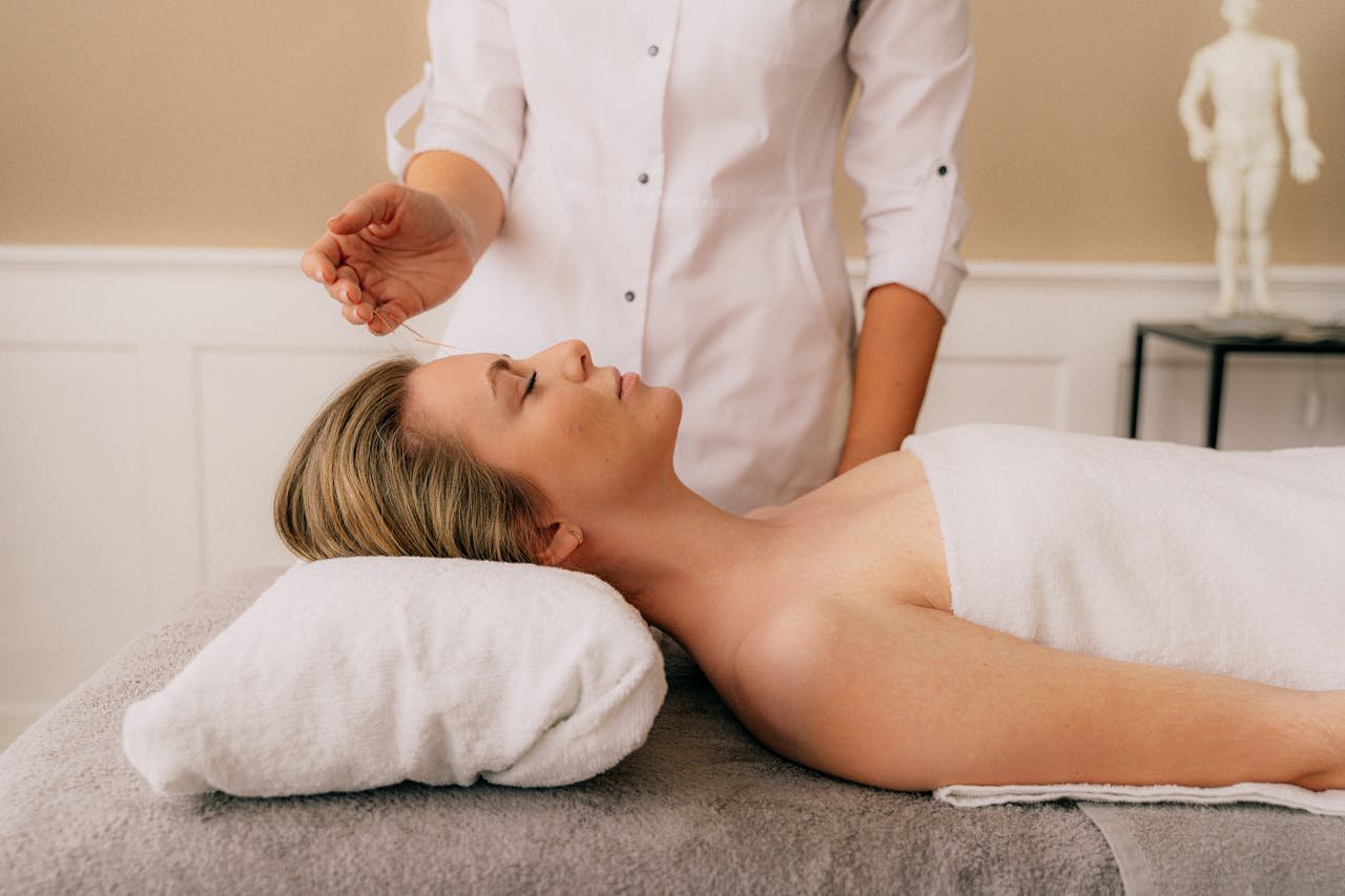 A woman receiving a relaxing acupuncture session on a massage table indoors.